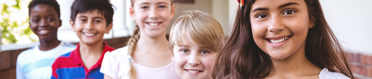 Five smiling students pose outside