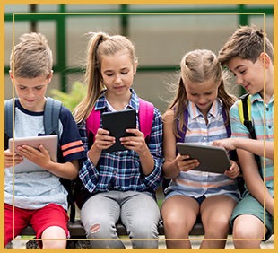 Four students using tablets outside